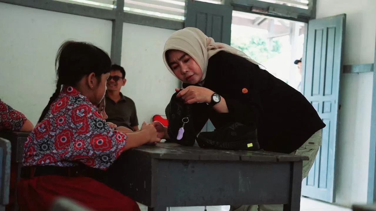 SEPATU: Kadisdikbud Provinsi Kalbar Rita memberikan sepatu pada anak SD Tanjung Lokang. (MIRZA/PONTIANAK POST)