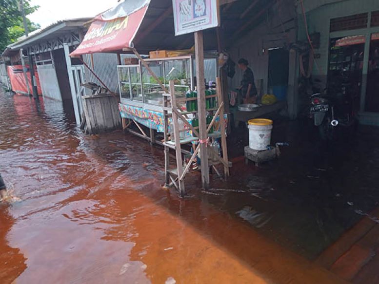 TETAP BUKA: Warga di Jalan Mendawai yang kebanjiran tetap berusaha mencari rezeki meski dikepung bencana, Jumat (15/3/2024). (SABRI YANUR/RADAR SAMPIT)