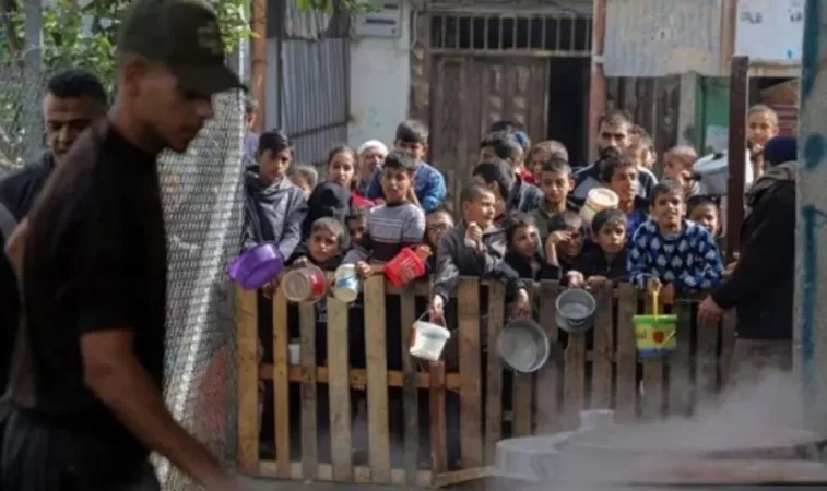 Para warga dan anak-anak, menunggu di pagar untuk mendapatkan bantuan makanan di Kota Rafah, Gaza, pada 19 November 2023. (Rizek Abdeljawad/Xinhua)