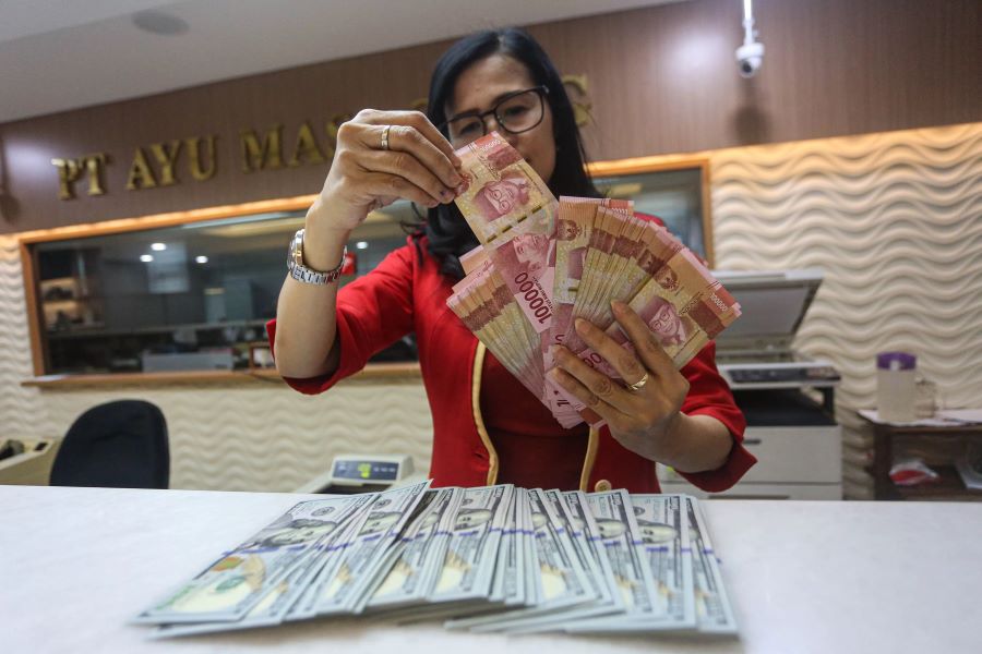 Karyawati menunjukkan mata uang rupiah dan dolar Amerika Serikat di tempat penukaran uang asing Agung Masayu di Jakarta, Selasa (24/10/2023). (MIFTAHUL HAYAT/ JAWA POS)