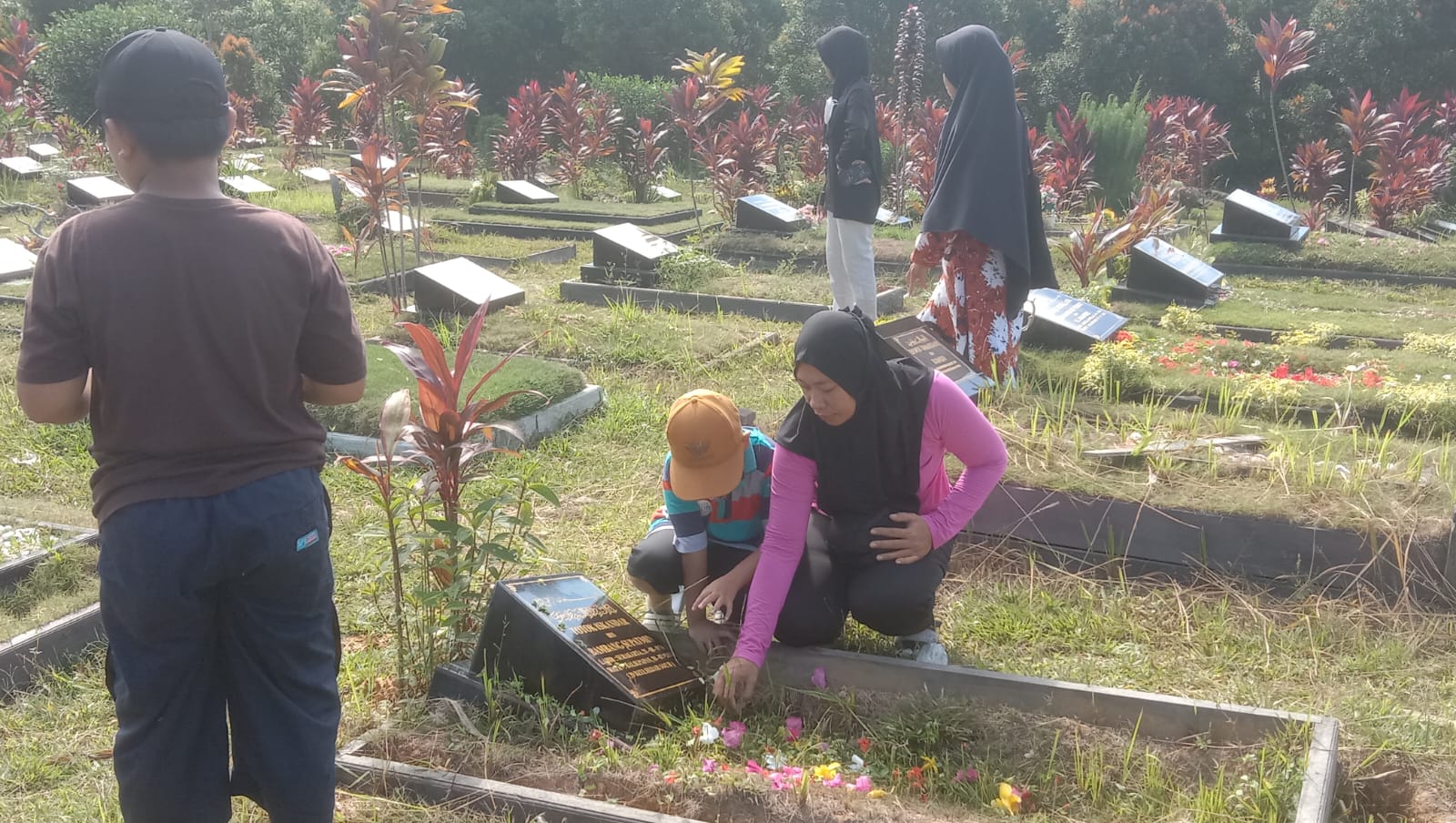 Peziarah tampak membersihkan sebuah makam korban Covid-19 di TPU Terpadu Covid-19, KM 17, Karang Joang, Senin (8/4/2024).