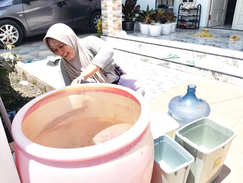 TAMPUNG AIR: Gegara air leding mati, warga Sungai Ulin, Banjarbaru terpaksa menampung air hujan untuk memenuhi kebutuhan sehari-hari. (FOTO: FADLAN ZAKIRI/RADAR BANJARMASIN)