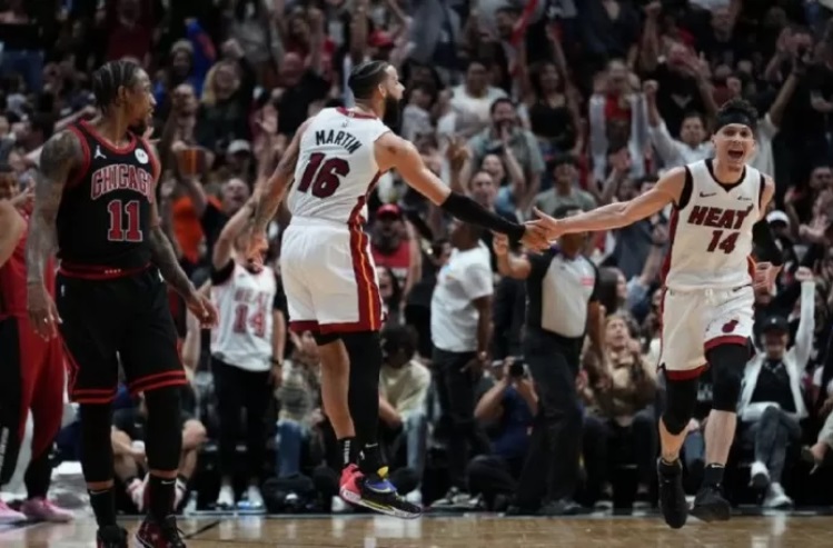 Pemain Miami Heat Tyler Herro (kanan) merayakan tripoin yang dibuatnya bersama Caleb Martin (tengah) saat timnya melawan Chicago Bulls pada babak play-in di Kaseya Center Miami, Florida.