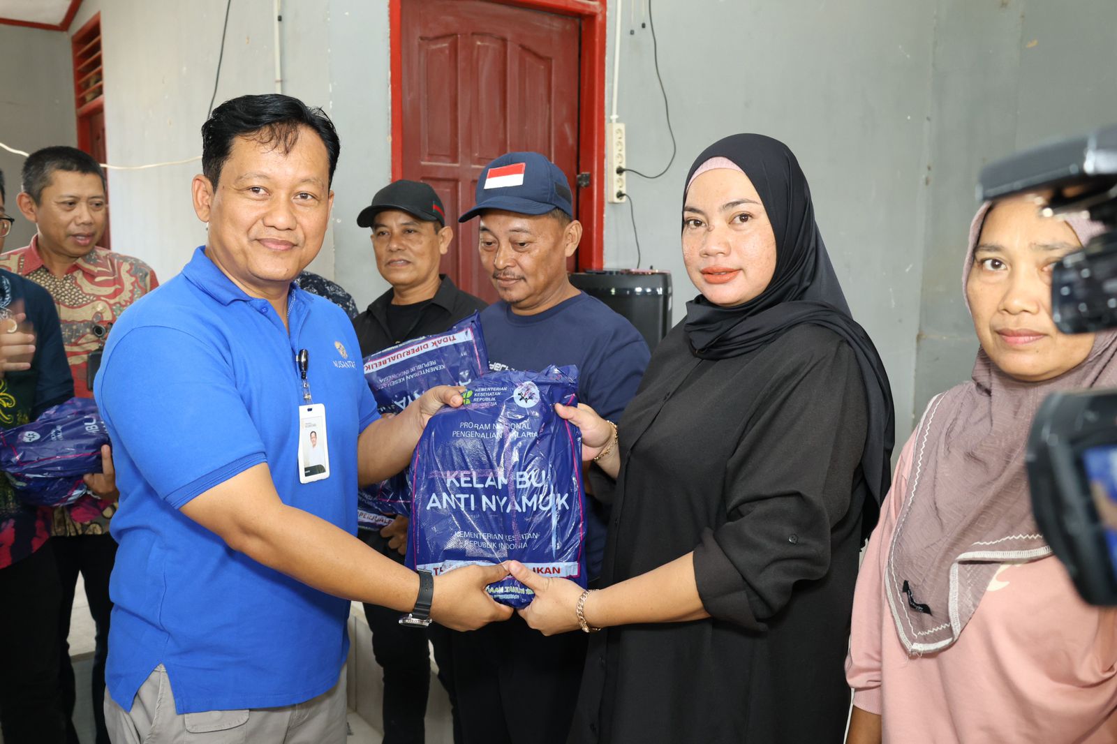 Direktur Pelayanan Dasar Otorita IKN Suwito menyerahkan kelambu kepada perwakilan warga.