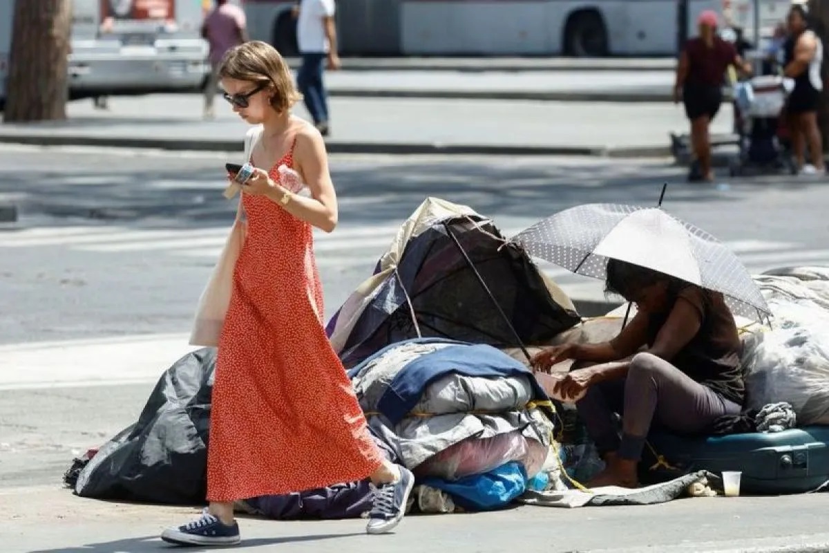 Seorang tunawisma berlindung dari sengatan matahari dengan payung di dekat stasiun kereta Termini saat gelombang panas melanda di Roma, Italia, 21 Juli 2023. (REUTERS/Guglielmo Mangiapane)