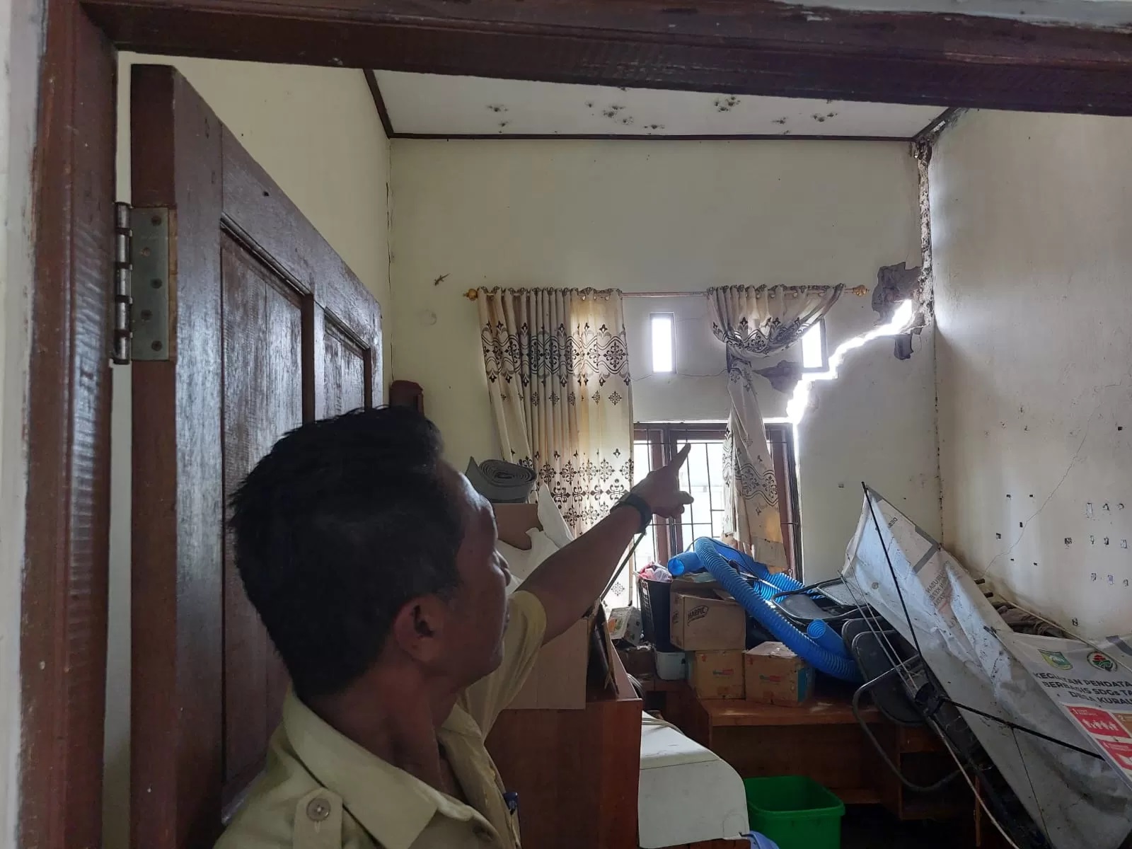 WAS-WAS : Kepala Desa Kurau Utara, Bahrani B menunjukkan dinding Kantor Desa yang retak.(Foto: Norsalim Yahya/Radar Banjarmasin)