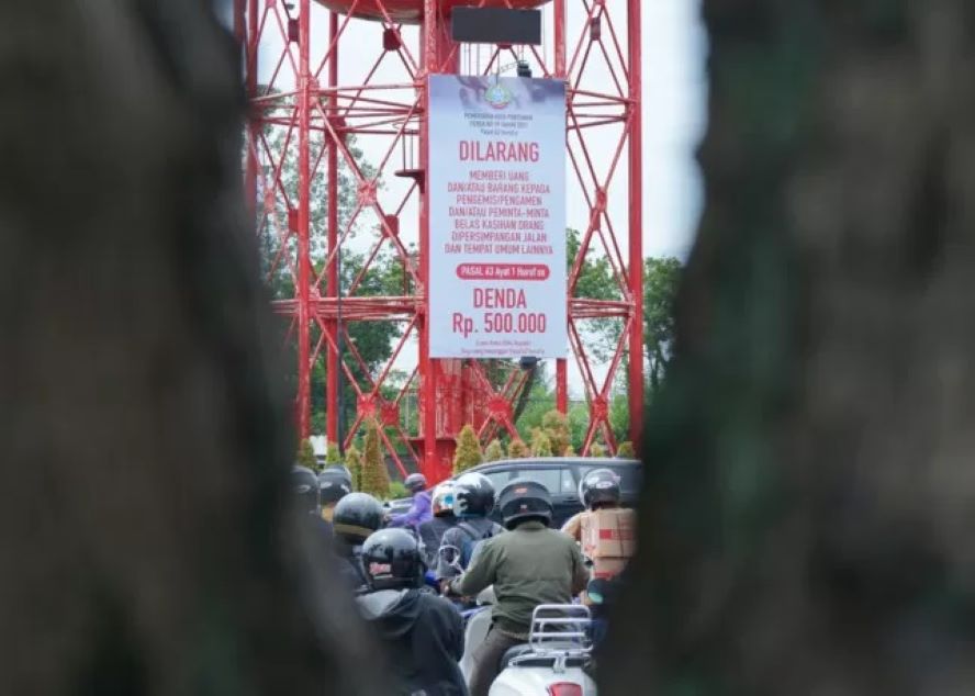 IMBAUAN: Baliho tentang larangan pemberian uang kepada gelandangan dan pengemis di perempatan lampu merah Kantor Pajak kembali dipasang oleh Dinas Sosial Kota Pontianak, Senin (12/6). (HARYADI)