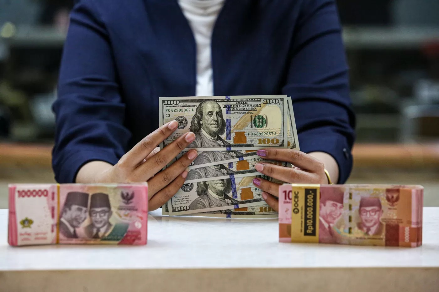 Karyawan menunjukan uang dolar Amerika Serikat (AS) dan Rupiah di salah satu gerai penukaran mata uang asing di Jakarta. (MIFTAHUL HAYAT/JAWA POS)