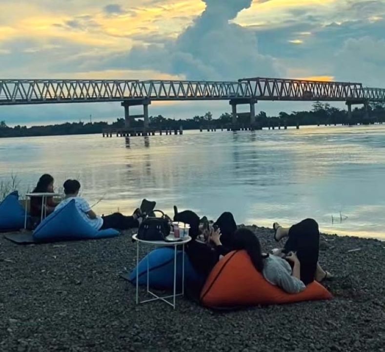 BERSANTAI: Warga menikmati keindahan matahari terbenam dengan view Jembatan Pulau Telo. (SABRIANOOR/RADAR SAMPIT)