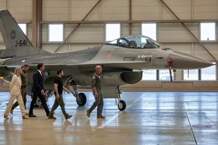 Volodymyr Zelenskiy, Presiden Ukraina, kedua dari kanan, dan Mark Rutte, Perdana Menteri Belanda, tengah, saat meninjau hanggar yang berisi jet tempur F-16. Ksenia Kuleshova/Bloomberg)