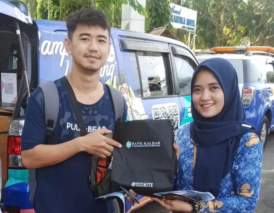 Petugas Bapenda memberikan suvenir kepada wajib pajak kendaraan yang membayar menggunakan Qris. (IST)