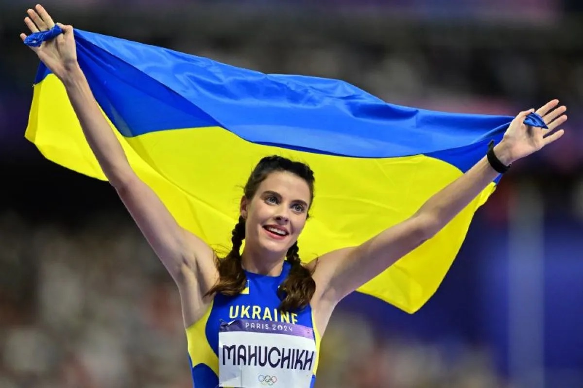 Atlet lompat tinggi Ukraina Yaroslava Mahuchikh merayakan keberhasilan meraih medali emas dengan membentangkan bendera kebangsaannya usai final atletik nomor ini dalam Olimpiade Paris 2024.