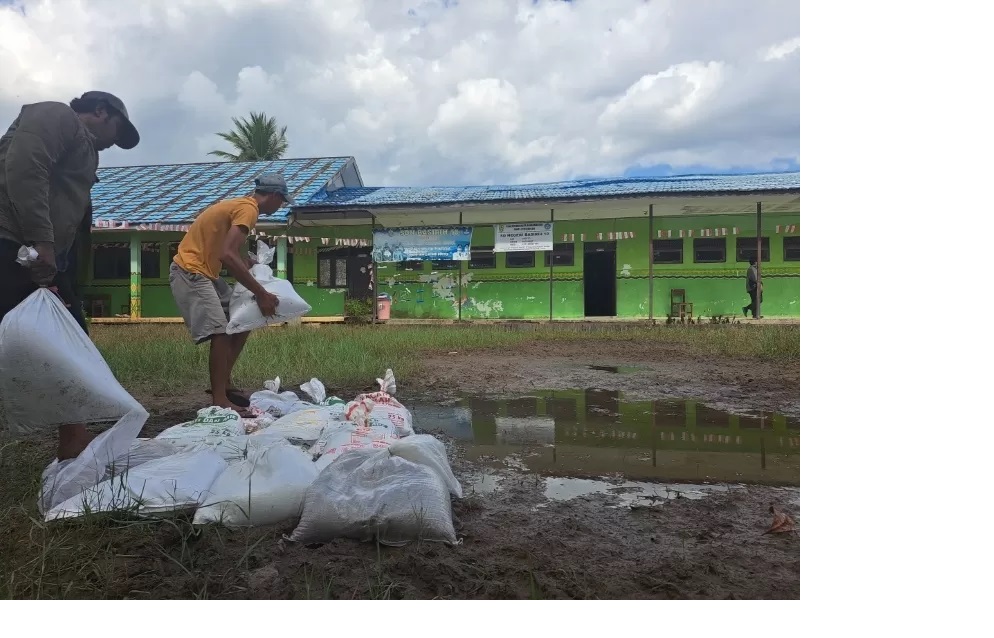 DITIMBUN: Pekerja proyek menimbun halaman SDN Basirih 10 yang berlumpur dengan pasir dan kerikil. (Foto: WAHYU RAMADHAN/RADAR BANJARMASIN)