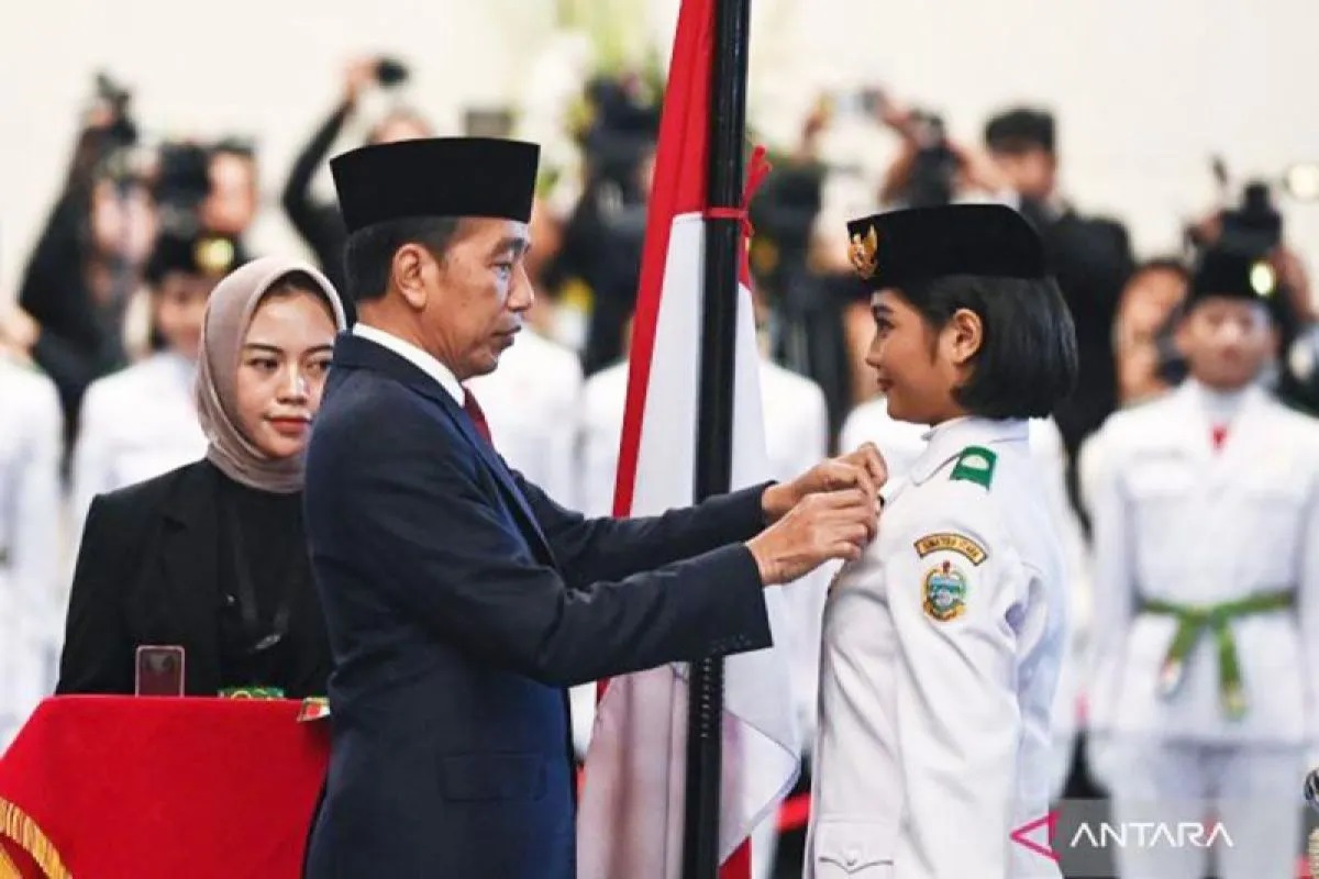 Presiden Joko Widodo (tengah) selaku pembina upacara menyematkan lencana kepada anggota Paskibraka 2024 asal Sumatera Utara Violetha Agryka Sianturi.