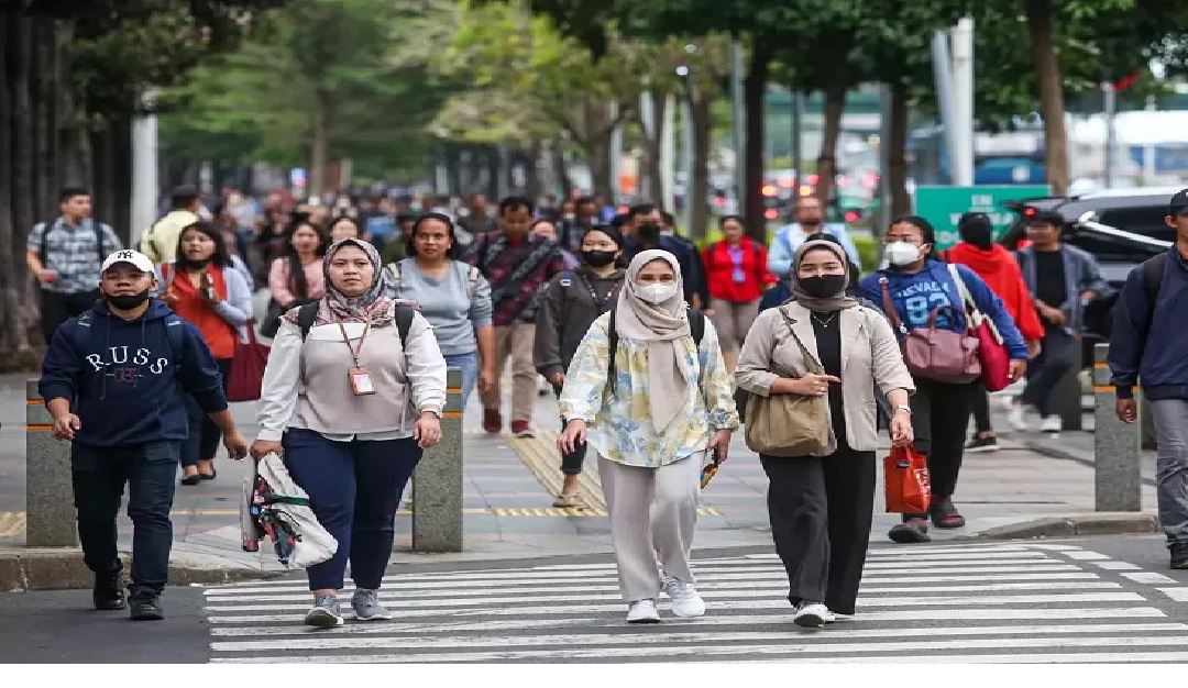Para pekerja berjalan saat jam pulang kerja di kawasan Jalan Sudirman, Jakarta.