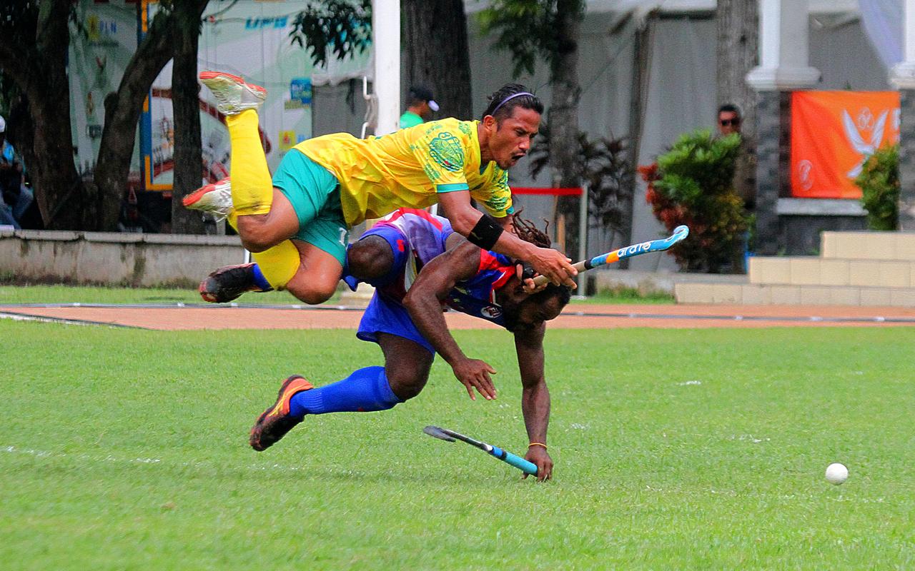 Atlet Hoki Outdoor Putra Kaltim , Ardam (atas) berebut bola dengan atlet Hoki Outdoor putra Papua, Lukas Ronald Mandowen pada pertandingan penyisihan Hoki Outdoor putra di Lapangan Serbaguna Outdoor.