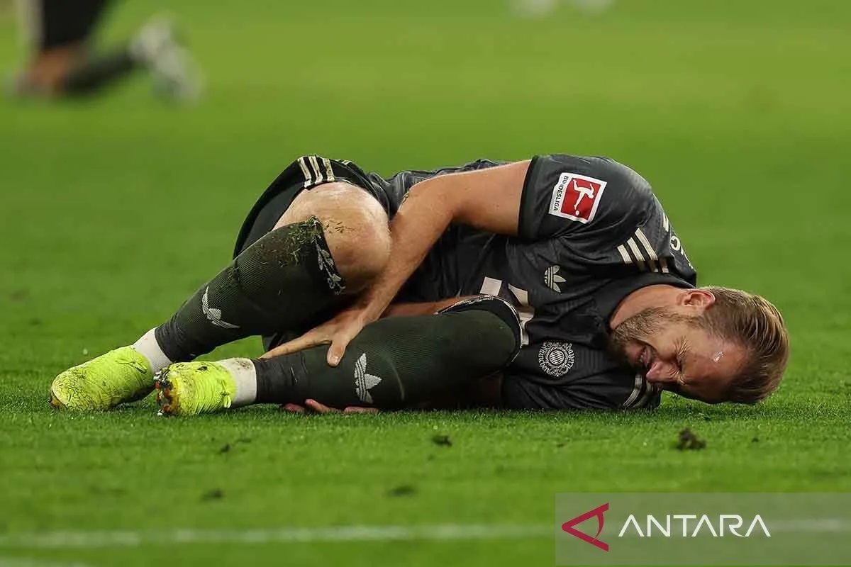 Pemain Bayern Munich Harry Kane memegangi kakinya saat melawan Bayer Leverkusen.
