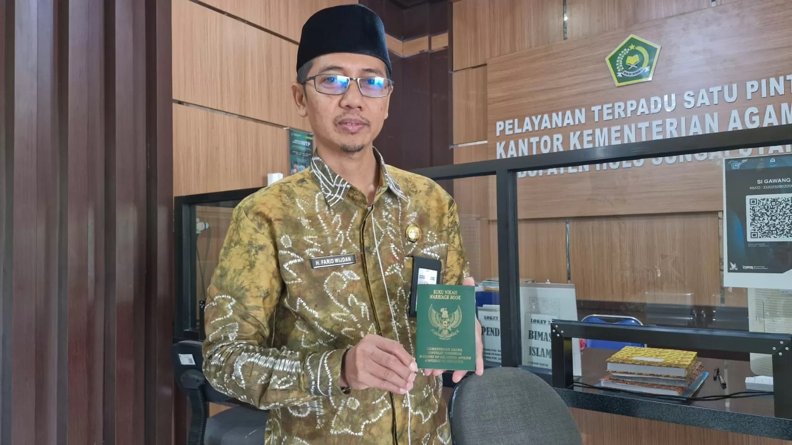 INFORMASI:Kasi Binmas Kantor Kemenag HSU H Farid, memperlihatkan buku nikah model terbaru tahun 2024.(Foto: Kemenag HSU/Radar Banjarmasin)
