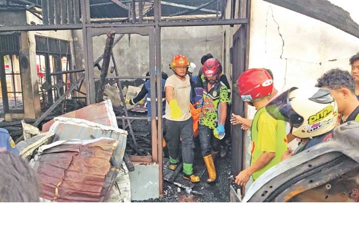 TELAN KORBAN JIWA: Petugas mengevakuasi jenazah korban kebakaran di Jalan Raying Suring, Palangka Raya, Selasa (31/12) siang.