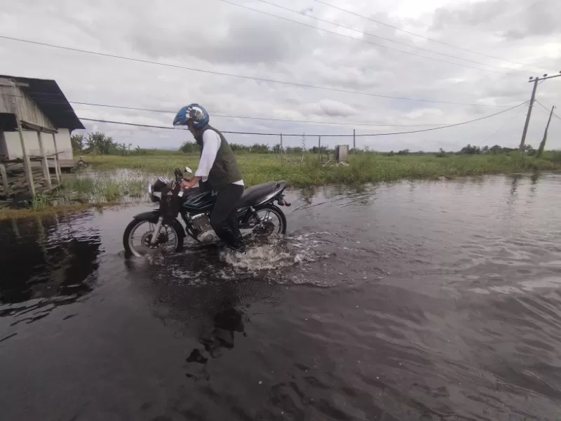 MOGOK : Sejumlah motor warga mendadak mati akibat nekat menerjang tingginya genangan banjir di jalan penghubung Desa Tungkaran dan Desa Keramat Baru, Kabupaten Banjar, Rabu (1/1/2025) (Foto: FADLAN ZA