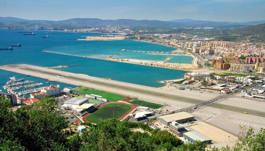 Bandara Internasional Gibraltar (Gibraltar).  Lokasi Gibraltar (Teritori Inggris di Spanyol). Tata letak landasan pacu yang unik dan interseksi dengan jalan raya umum.