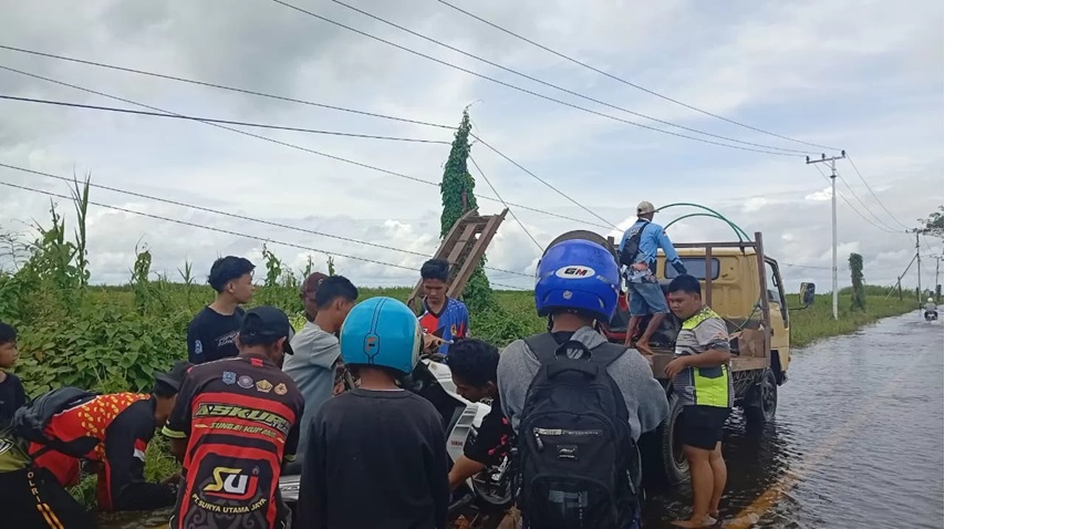 ANGKUT: Beberapa relawan mangangkut motor warga ke atas truk untuk menyeberangi banjir di jalur Kandangan-Nagara. (M Padil Ihsan/Radar Banjarmasin)