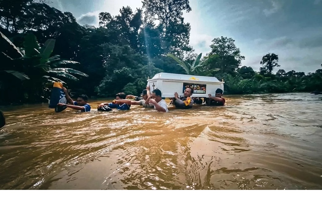 Warga dan polisi memanggul peti jenazah menembus banjir setinggi dada orang dewasa di Kecamatan Beduai, Kabupaten Sanggau, Minggu (11/1), akibat akses jalan terputus. (Istimewa)