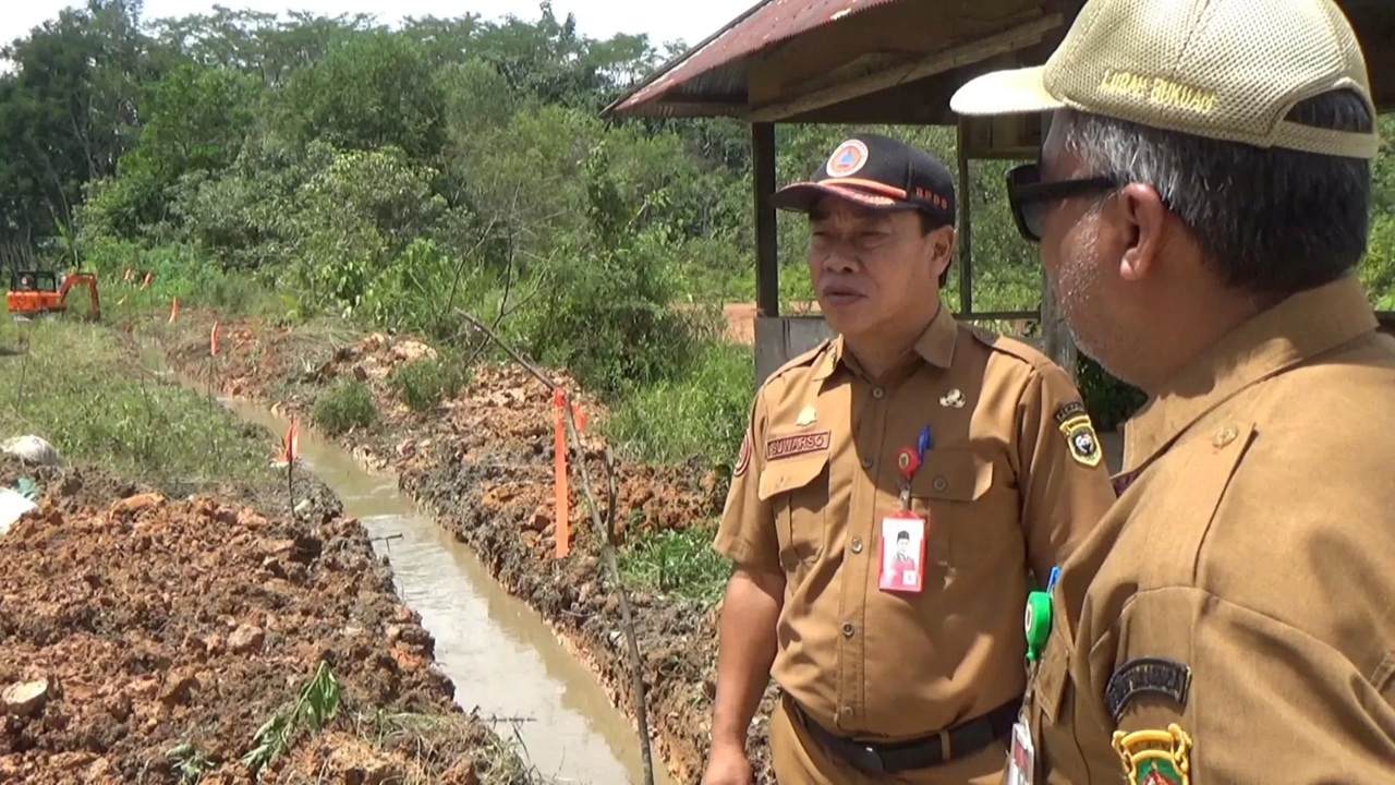 MINIMALISASI. Kepala Pelaksana BPBD Kota Samarinda, Suwarso, memimpin langsung pembuatan aliran sungai untuk mengantisipasi potensi luapan air dari eks kolam tambang di Kelurahan Bukuan. (IST)