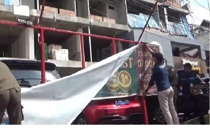 Petugas Satpol PP menurunkan baliho ilegal di salah satu ruas jalan protokol Balikpapan sebagai bagian dari penertiban reklame tak berizin dan penunggak pajak.