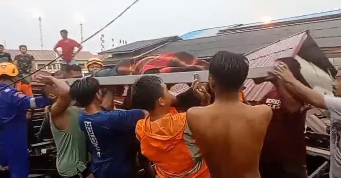 Warga bersama petugas mengevakuasi jenazah pedagang yang tewas tertimpa bangunan roboh akibat hujan deras dan angin kencang di kawasan pesisir Balikpapan, Minggu (8/2/2026).
