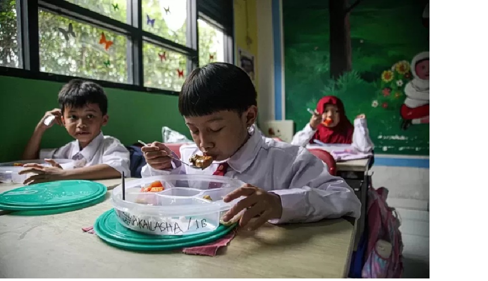 DIHENTIKAN SEMENTARA: Sejumlah siswa sekolah dasar saat menyantap makan bergizi gratis di Kota Tangerang. (HANUNG HAMBARA/JAWA POS) 