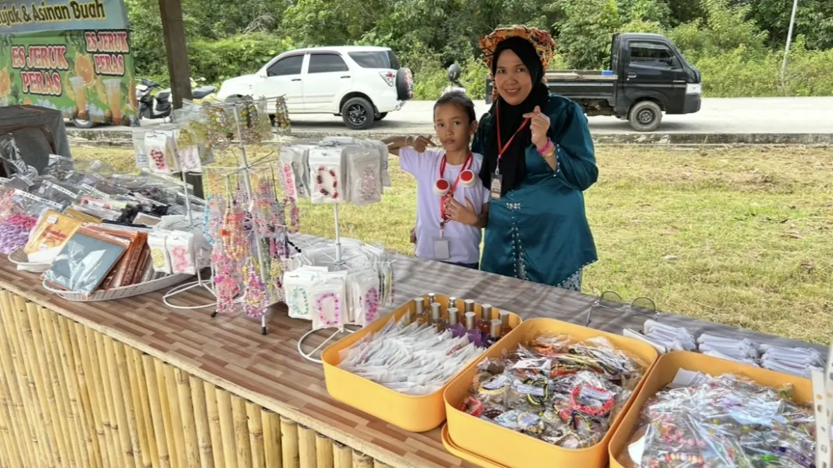 

KERAJINAN TANGAN: Rafania di sela mempersiapkan daganganya bersama ibunya di stan bazar UMKM Pakot Ngeno di Rumah Adat Kuta Rekan Tatau Penajam, Jumat, Mei 2026. Jumat ini, 15 Mei 2026, dia kembali hadir. PROKAL.CO