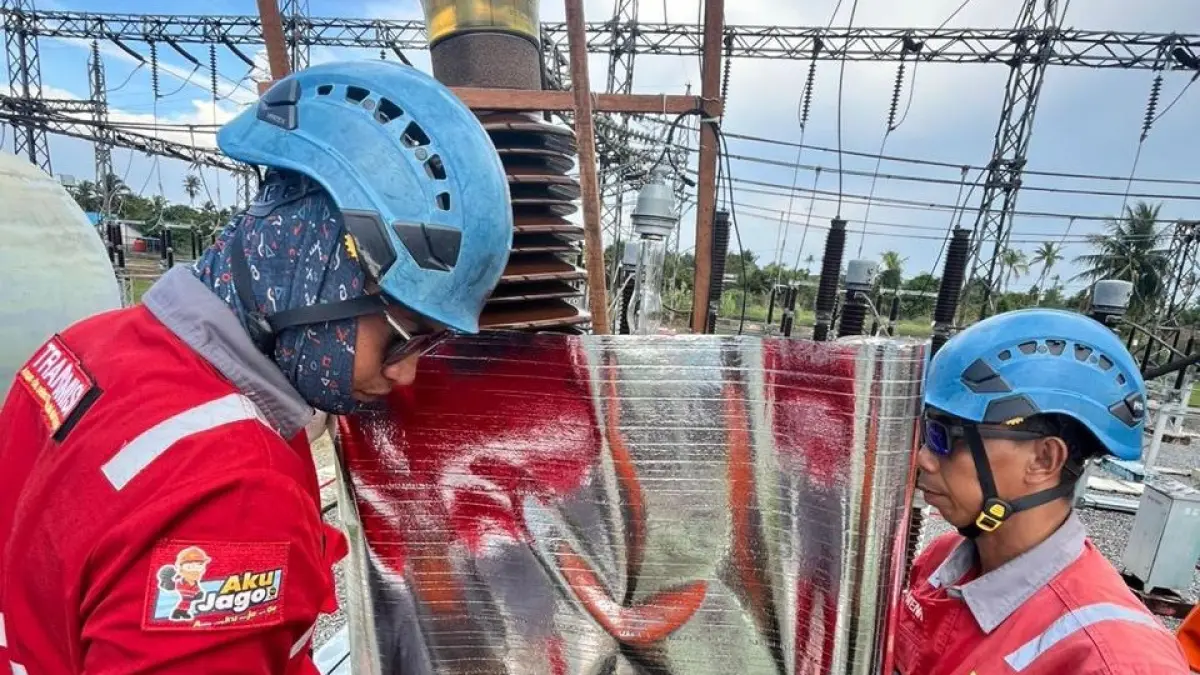 Dua orang tim pemeliharaan memasang insulating blanket sebagai pelindung sementara pada peralatan tegangan tinggi di gardu induk. 