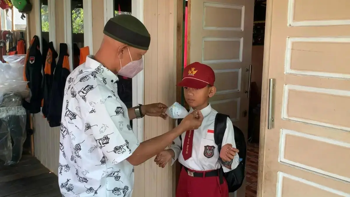 WASPADA: Orangtua murid di Landasan Ulin Selatan memakaikan masker kepada anaknya sebelum berangkat sekolah di tengah kabut asap karhutla. (Foto: Sheilla/Radar Banjarmasin)