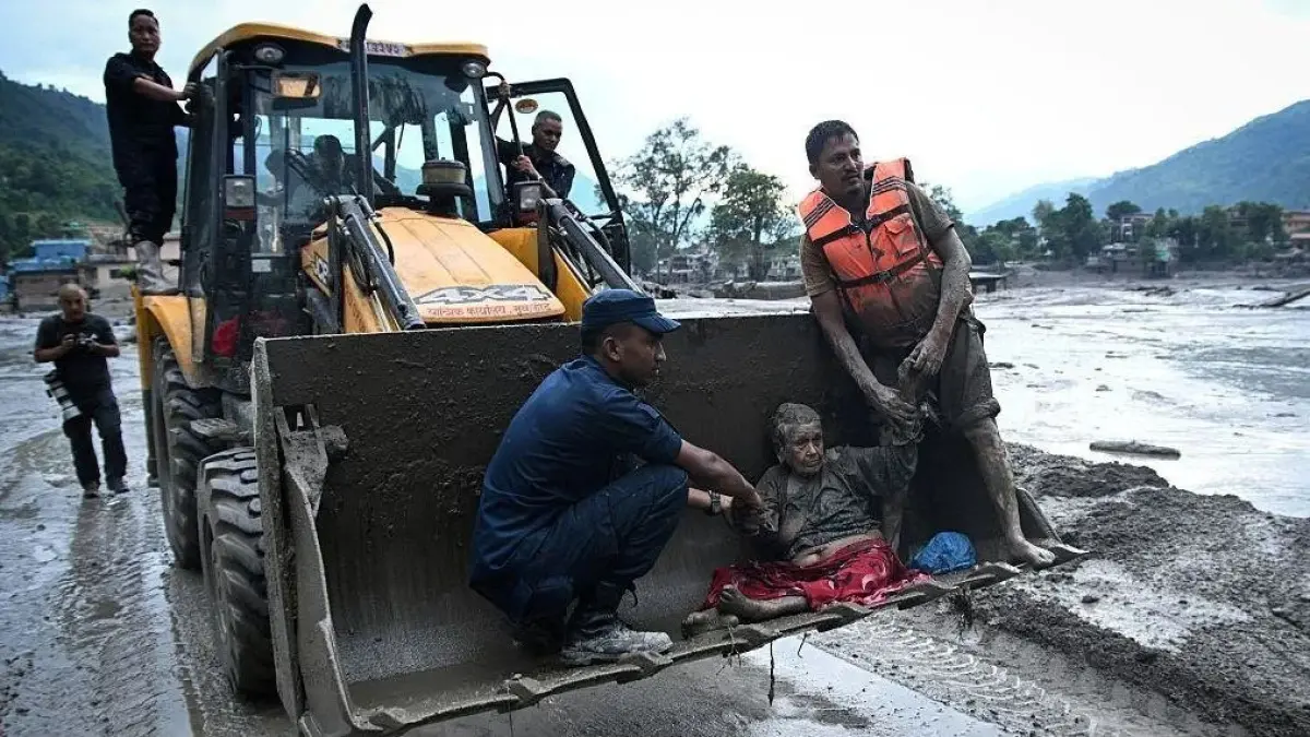 Seorang warga diselamatkan warga lainnya dalam banjir bandang di Nepal.