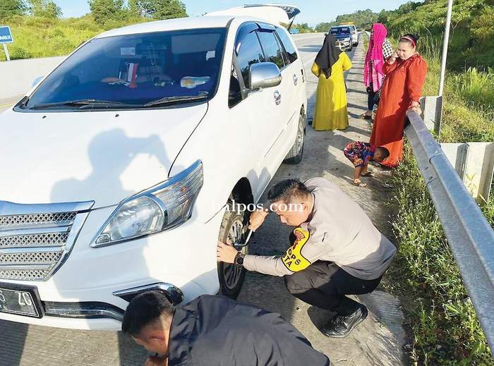HUMANIS: Kapolresta Balikpa­pan AKBP Anton Firmanto meng­gantikan ban mobil pecah milik warga agar bisa melan­jutkan perjalanan lagi.