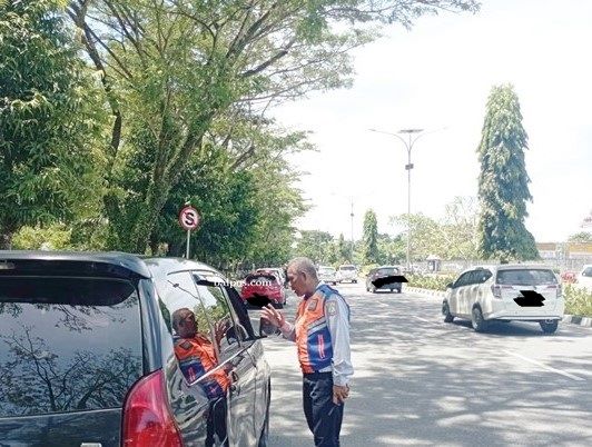 TERTIBKAN : Petugas Dishub Balikpapan saat melakukan teguran lisan hingga memasang stiker pada mobil yang kerap parkir sembarangan depan bandara.foto : ist