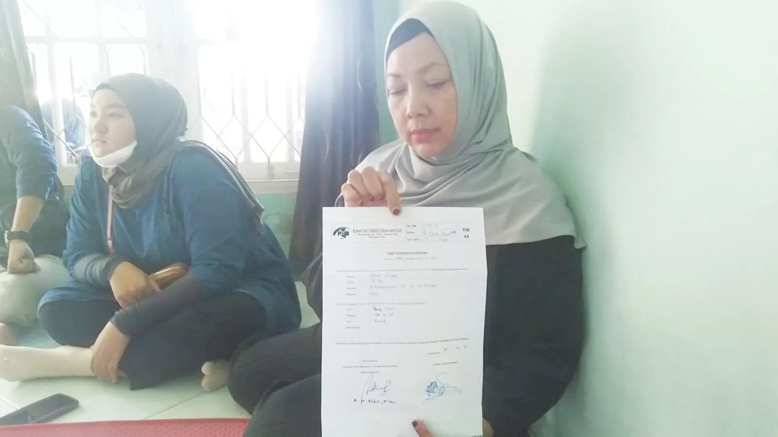 BERDUKA: Kerabat DA saat menunjukkan Surat Keterangan gan Kematian (SKK) dari rumah sakit. DA ditemukan pingsan di rumahnya dan beberapa jam kemudian dinyatakan meninggal dunia. (DAYAT/BALPOS)