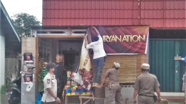 DICOPOT: Satpol PP Kota Balikpapan saat menurunkan reklame iklan rokok. Pelarangan total iklan rokok di Balikpapan dinilai mengancam perekonomian, khususnya pelaku usaha reklame. IST