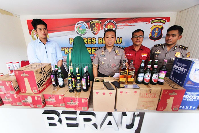 KONFERENSI PERS: Polisi saat menunjukkan pelaku penjualan miras secara ilegal (jilbab hijau) serta barang buktinya berupa ratusan botol miras, kemarin (18/2).