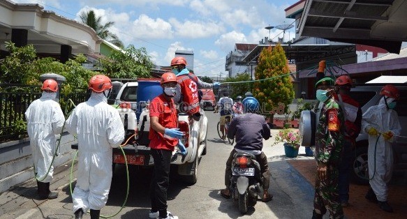 SASAR PERMUKIMAN: Relawan PMI Berau saat melakukan penyemprotan disinfektan di Gang Nangka, Tanjung Redeb, kemarin (16/4).