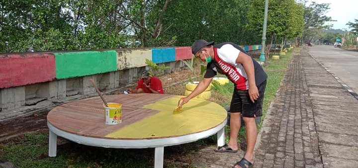 TEMPAT BERSANTAI: Lurah Sambaliung Didi Mulyadi saat mengecat tempat duduk di Tepian Sambaliung yang merupakan barang bekas dari gulungan kabel.