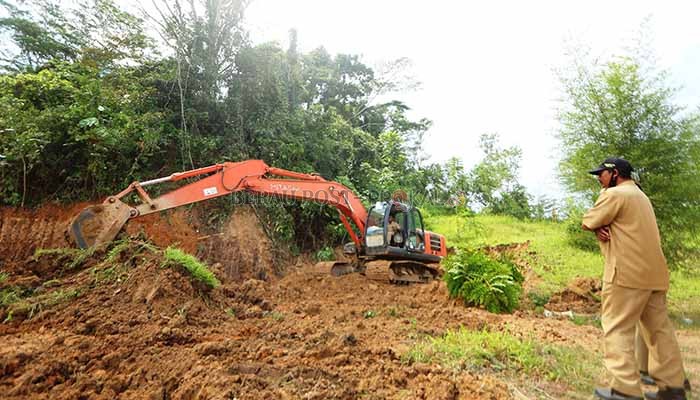 MULAI DIKERJAKAN: Nampak petugas mulai melakukan pelebaran pemakaman Covid-19 menggunakan satu unit ekskavator.