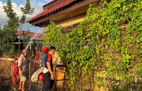 PROSES PEMADAMAN: Petugas Damkar bersama warga setempat memadamkan api di bagian plafon KUA Tanjung Redeb.