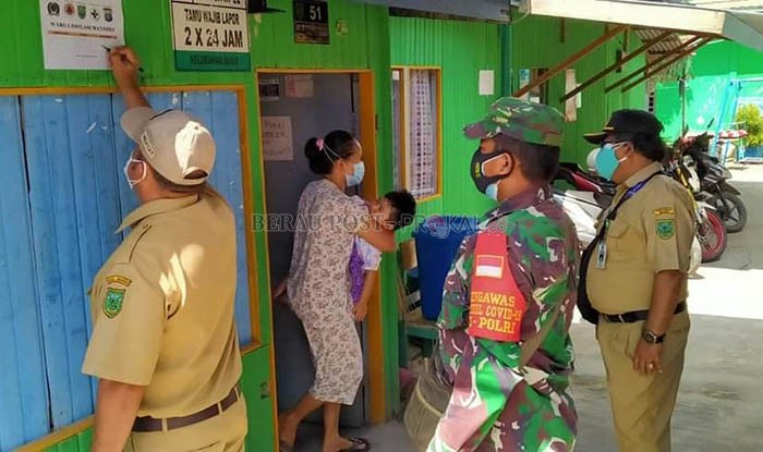 TEMPELI STIKER: Petugas Satgas Kelurahan Bugis saat menempeli stiker di kediaman pasien isolasi mandiri, beberapa waktu lalu.