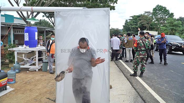 JAGA PERBATASAN: Masyarakat harus disiram cairan disinfektan saat ingin melintasi jalur perbatasan Berau-Bulungan, beberapa waktu lalu. Penjagaan ketat di perbatasan, kembali akan dilakukan pemkab Berau, seiring status PPKM yang kembali naik ke level 3.