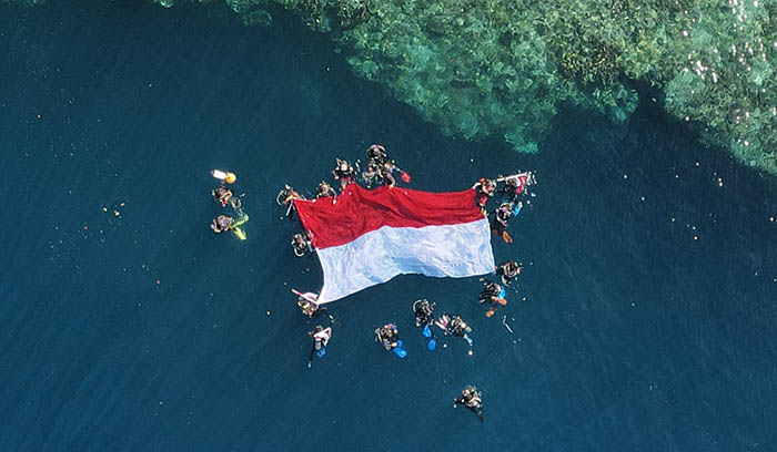 DI PULAU TERLUAR: Wakapolres Berau Kompol Ramadhanil bersama Pembina Berau Jurnalis Divers Agus Tantomo dan beberapa anggota PWI Berau, mengibarkan bendera Marah Putih berukuran 7x4 meter di bawah laut Pulau Maratua.