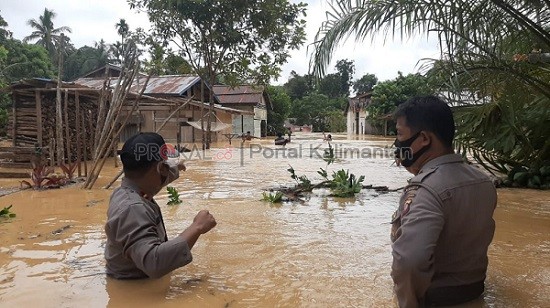 Petugas memantau rumah yang terendam ditengah banjir.