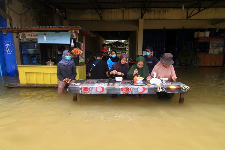 Sejumlah warga menyantap makanan di sebuah warung yang terendam banjir di Putussibau, Kabupaten Kapuas Hulu, Kalimantan Barat, Selasa (15/9/2020). Banjir setinggi 1-5 meter yang melanda Putussibau sejak Minggu (13/9/2020) hingga Selasa (15/9/2020) melumpu