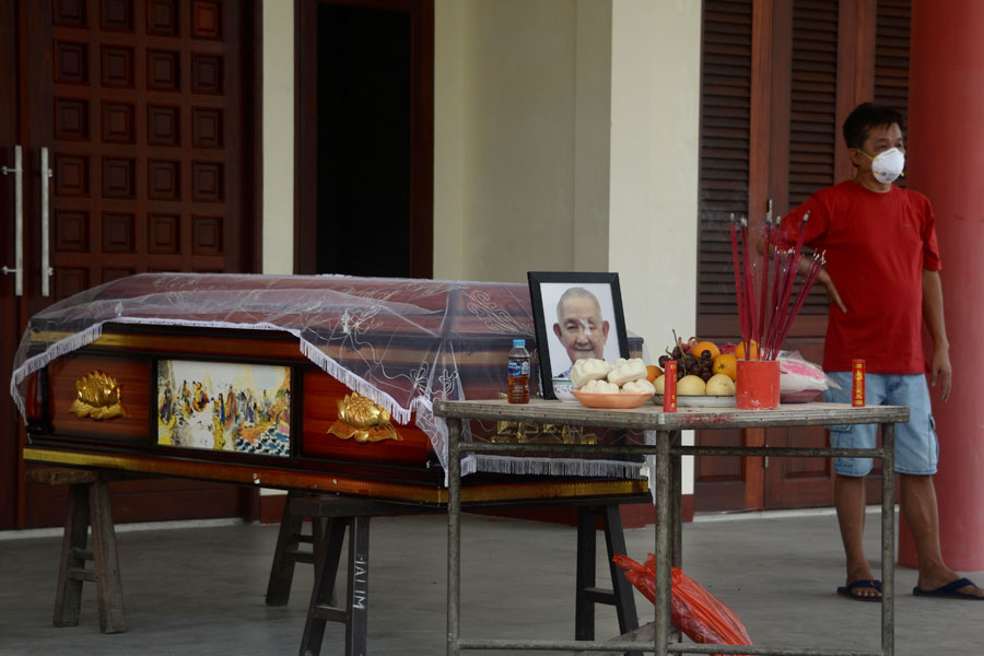 MENUNGGU ANTREAN: Seorang lelaki berdiri di samping peti jenazah keluarganya yang akan dikremasi di Krematorium Yayasan Halim Pontianak, di Jalan Adi Sucipto, Sungai Raya, Kubu Raya. Selama masa pandemi, permintaan kremasi melonjak dari sebelumnya. ARIEF